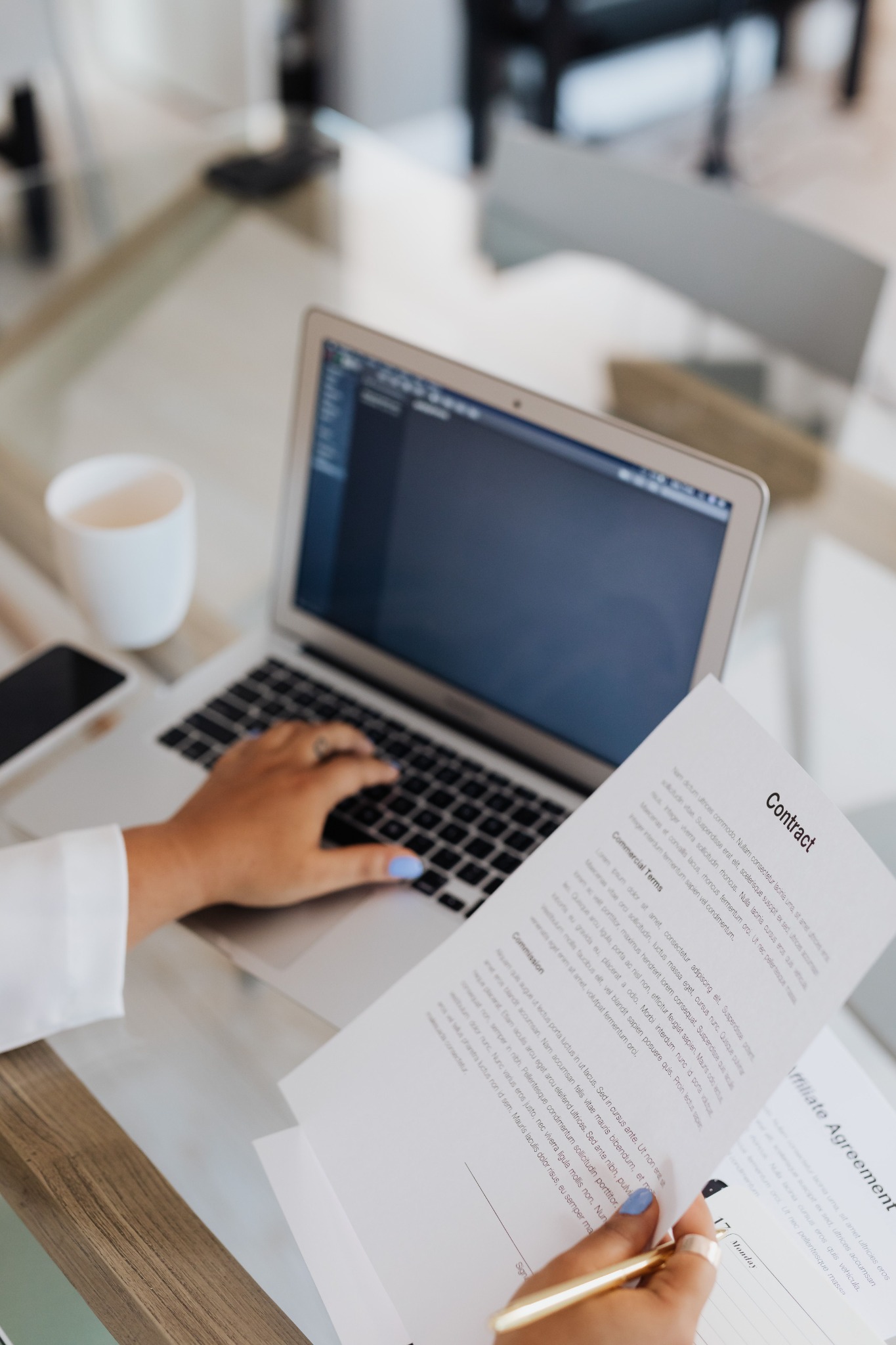 Professional reviewing a contract while working on a laptop